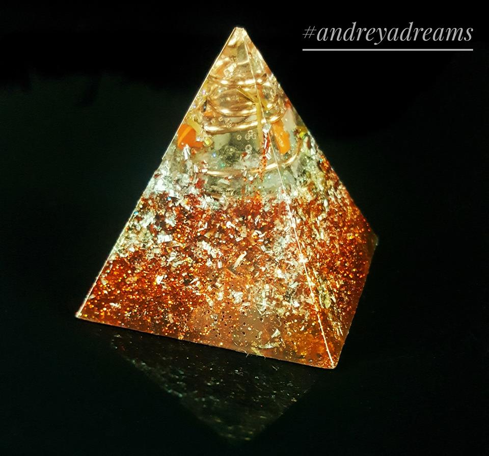 Piramide decorativa dourada e cobre sobre fundo preto