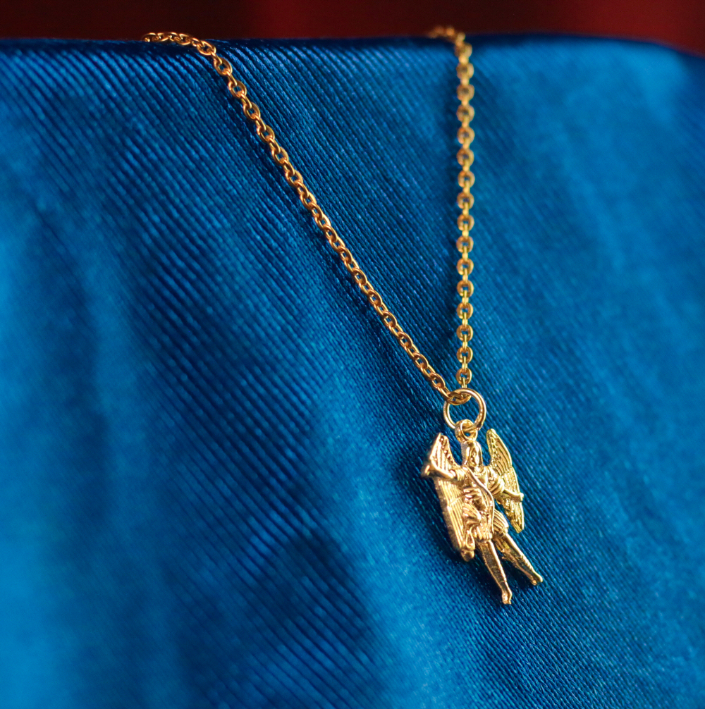 Arcanjo Miguel Dourado Colar dourado com pendente de anjo sobre tecido azul