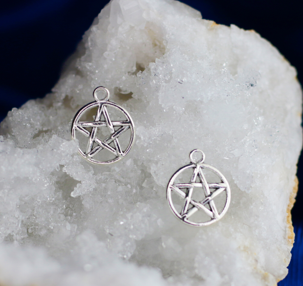 Pentagrama Par de pendentes em forma de estrela de cinco pontas prateadas sobre um cristal branco