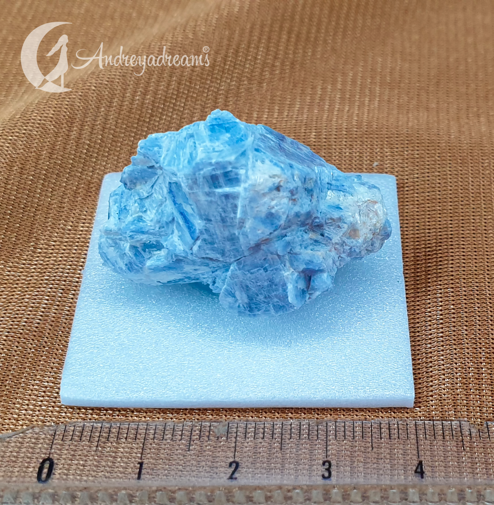Cianite Azul Roca mineral azul sobre base branca com régua em fundo castanho