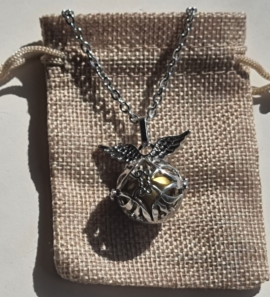 Chamador de Anjos com Asas Colar prateado com esfera decorada e asas sobre saco de tecido bege