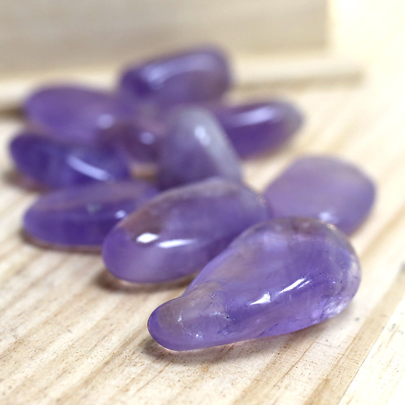 Ametista Pedras polidas de ametista roxa sobre superfície de madeira clara