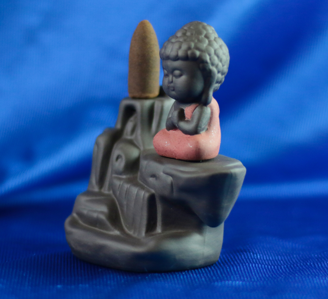 Cascata de Fumo Buda Vermelho Figura decorativa Buda sentado com incenso cone numa base cinzenta sobre tecido azul