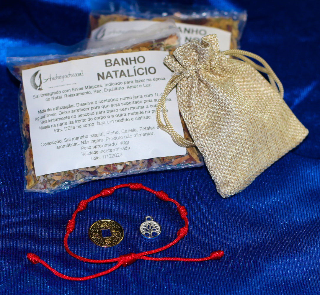 Kit Ano Novo Conjunto de sal aromatizado BANHO NATALÍCIO, saco dourado, pulseira vermelha e pendentes metálicos sobre fundo azul.