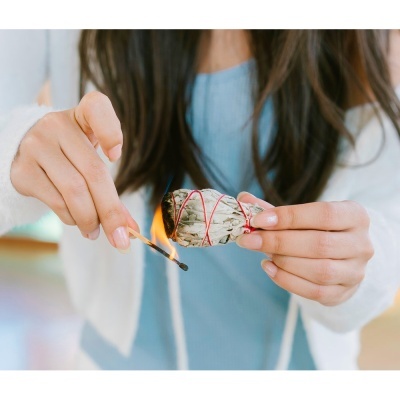 Pessoa segurando e a acender um feixe de ervas com fósforo