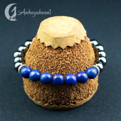 Pulseira de contas azuis, brancas e prateadas sobre suporte castanho texturado