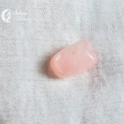 Pedra rosa clara polida sobre pano branco texturado com logo 'Andariva'.