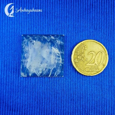 Pedra translúcida quadrada e moeda de 20 cêntimos sobre tecido azul