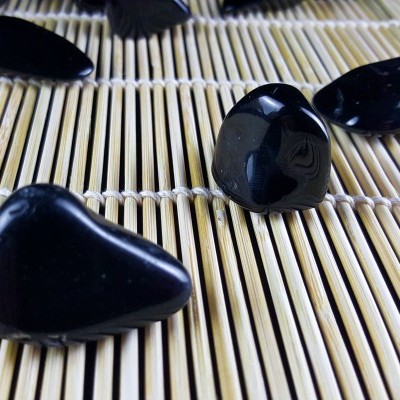 Pedras polidas pretas sobre esteira de bambu clara