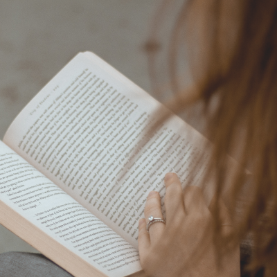 Pessoa a ler um livro aberto com texto e anéis nas mãos