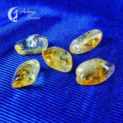 Cinco pedras polidas amarelas e transparentes sobre tecido azul