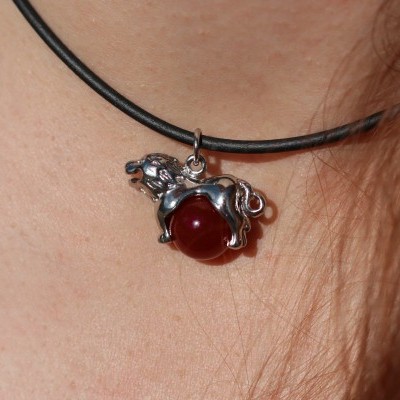 Colar com pendente de cavalo prateado com esfera vermelha em fio preto no pescoço