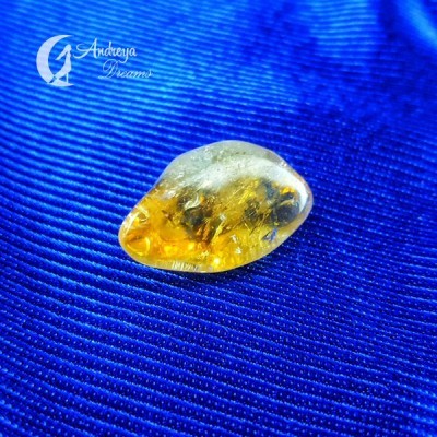 Pedra polida amarela e âmbar sobre tecido azul com texto Andreya Dreams