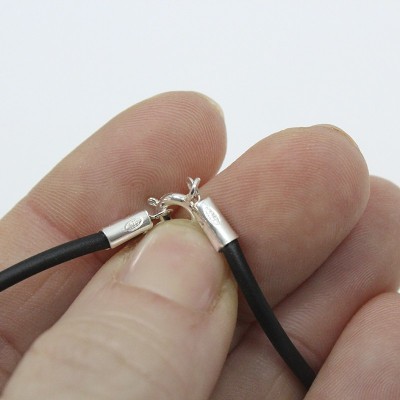 Colar com cabo preto e fecho metálico prateado sendo segurado por uma mão