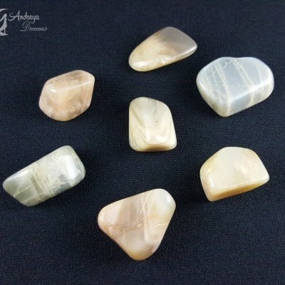 Sete pedras polidas coloridas sobre tecido preto com marca Andheya Dreams