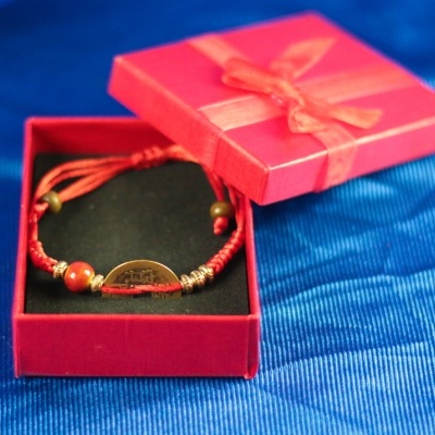 Pulseira vermelha numa caixa de presente vermelha com laço, sobre tecido azul