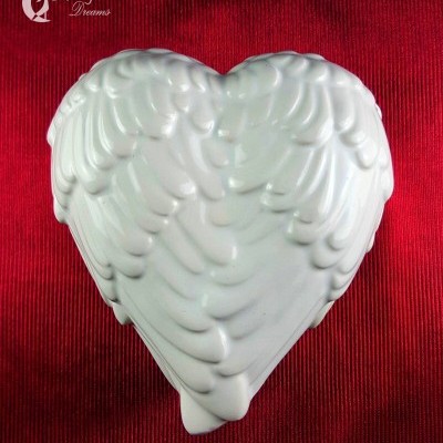 Escultura branca em forma de coração com textura de penas sobre fundo vermelho.