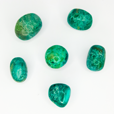 Cinco pedras verdes polidas dispostas sobre fundo branco.