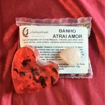 Pacote de sal consagrado e sabonete em forma de coração vermelho sobre tecido vermelho