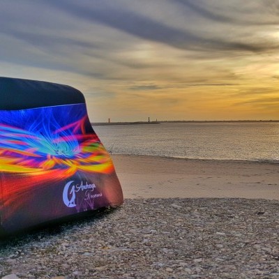 Mochila colorida com padrão abstrato na praia ao pôr do sol