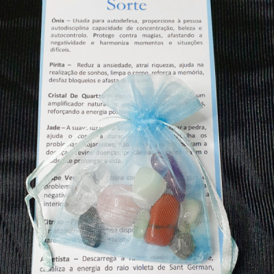 Saco azul com pedras variadas coloridas sobre folheto explicativo em português