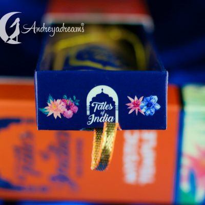 embalagem azul com flores e texto Tales of India com fita dourada