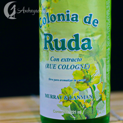 Colónia de Ruda em garrafa verde com rótulo branco e verde, texto em espanhol e imagem de folhas