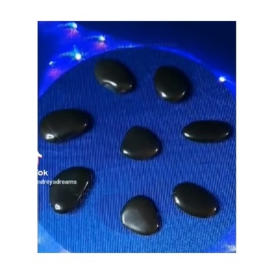 Pedras negras brilhantes sobre base azul com luzes no fundo