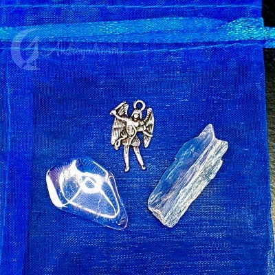 saquinho azul com duas pedras brancas e um pingente de anjo prateado