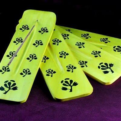 Quatro tábuas amarelas de madeira com desenho de folhas pretas sobre fundo roxo