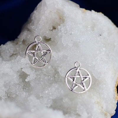 Par de pendentes em forma de estrela de cinco pontas prateadas sobre um cristal branco