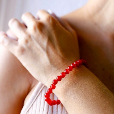 Pulseira vermelha de contas redondas no pulso de uma pessoa