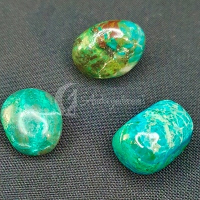 Três pedras polidas coloridas sobre tecido preto