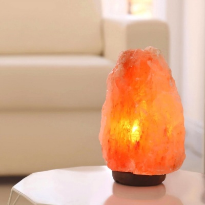 Lâmpada de sal do Himalaia laranja iluminada sobre mesa branca