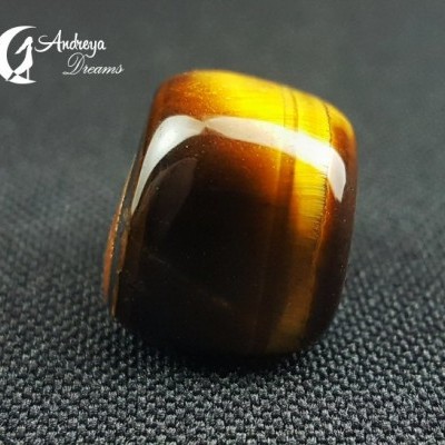 Cubo de pedra polida em tons castanho, amarelo e branco sobre tecido preto.