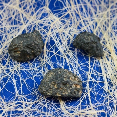 Três pedras pretas sobre rede fina branca e fundo azul