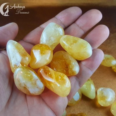 Pedras polidas amarelas e alaranjadas sobre mão humana