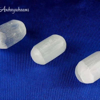 Três cápsulas translúcidas de cristal branco com textura estriada sobre fundo azul.