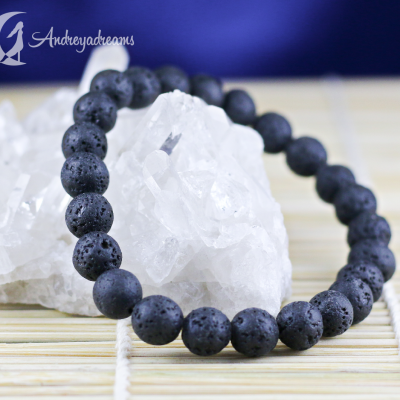 Pulseira preta de contas ásperas e lisas ao redor de cristal branco sobre superfície de madeira