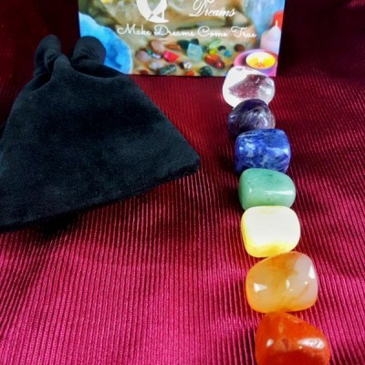 Conjunto de sete pedras coloridas e saco preto sobre tecido vermelho