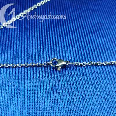 Corrente prateada com fecho de lagosta sobre tecido azul