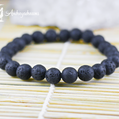 Pulseira de contas pretas texturizadas colocada em superfície clara ranhurada