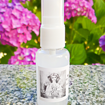 Frasco spray branco translúcido com etiqueta a preto e branco e fundo floral