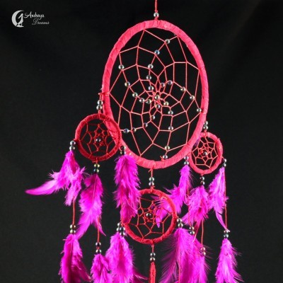 Apanhador de sonhos vermelho com penas rosa contra fundo preto