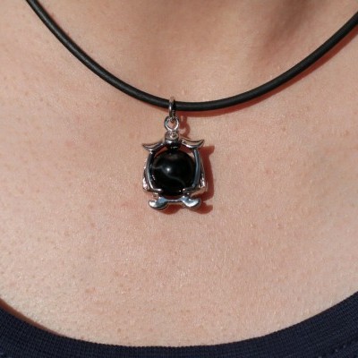 Colar com pendente de gato prateado com esfera preta ao peito.
