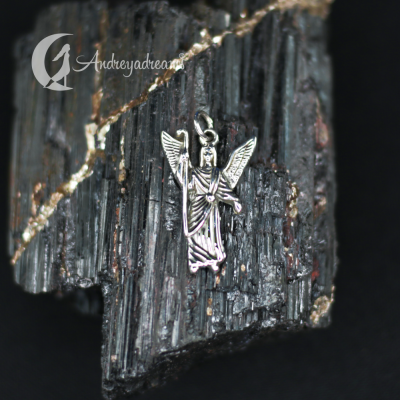 Pingente prateado de anjo sobre rocha escura com fissuras douradas