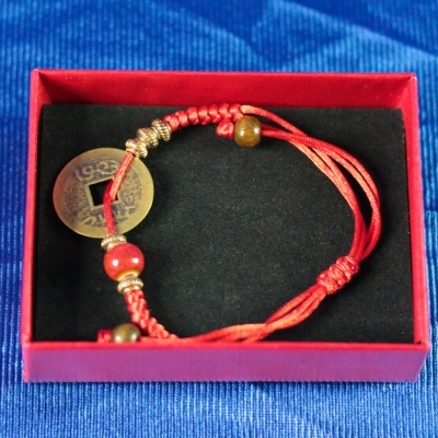 Pulseira vermelha com moeda chinesa numa caixa vermelha