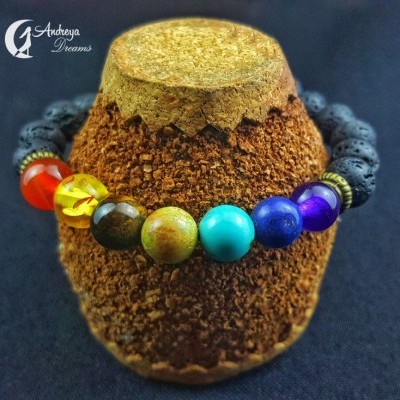 Pulseira colorida de contas redondas em suporte de cortiça com fundo preto e logo 'Andrezza Dreams'.