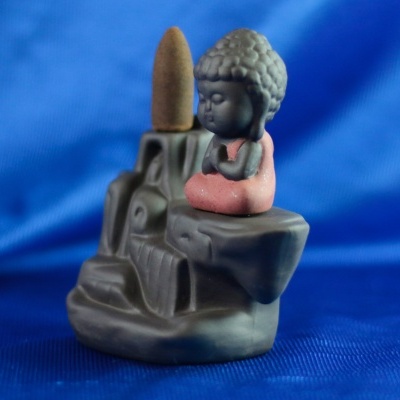 Figura decorativa Buda sentado com incenso cone numa base cinzenta sobre tecido azul
