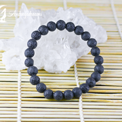 Pulseira de contas pretas porosas de pedra vulcânica sobre superfície de bambu com cristal branco ao fundo